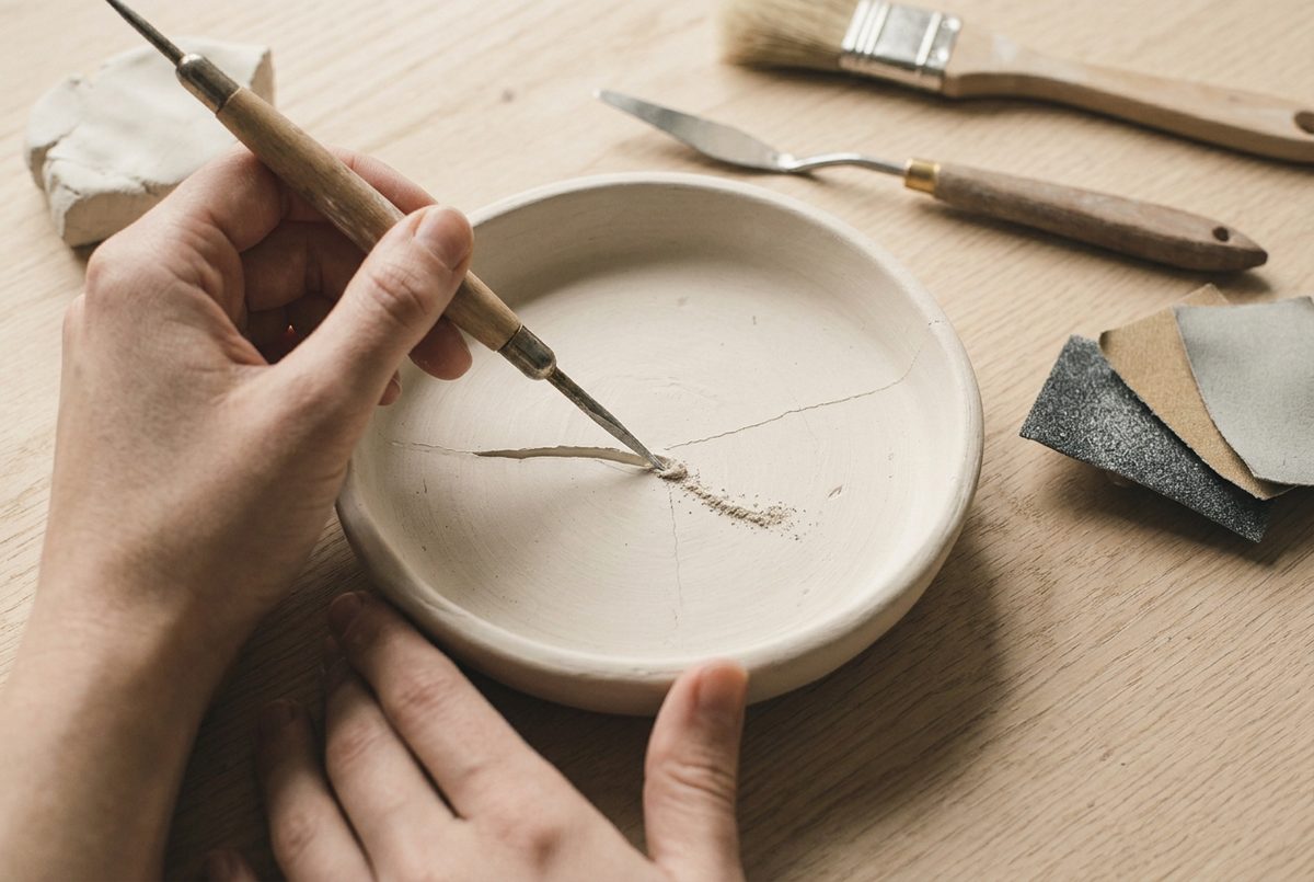 A pointed modelling tool widening a hairline crack into a shallow V