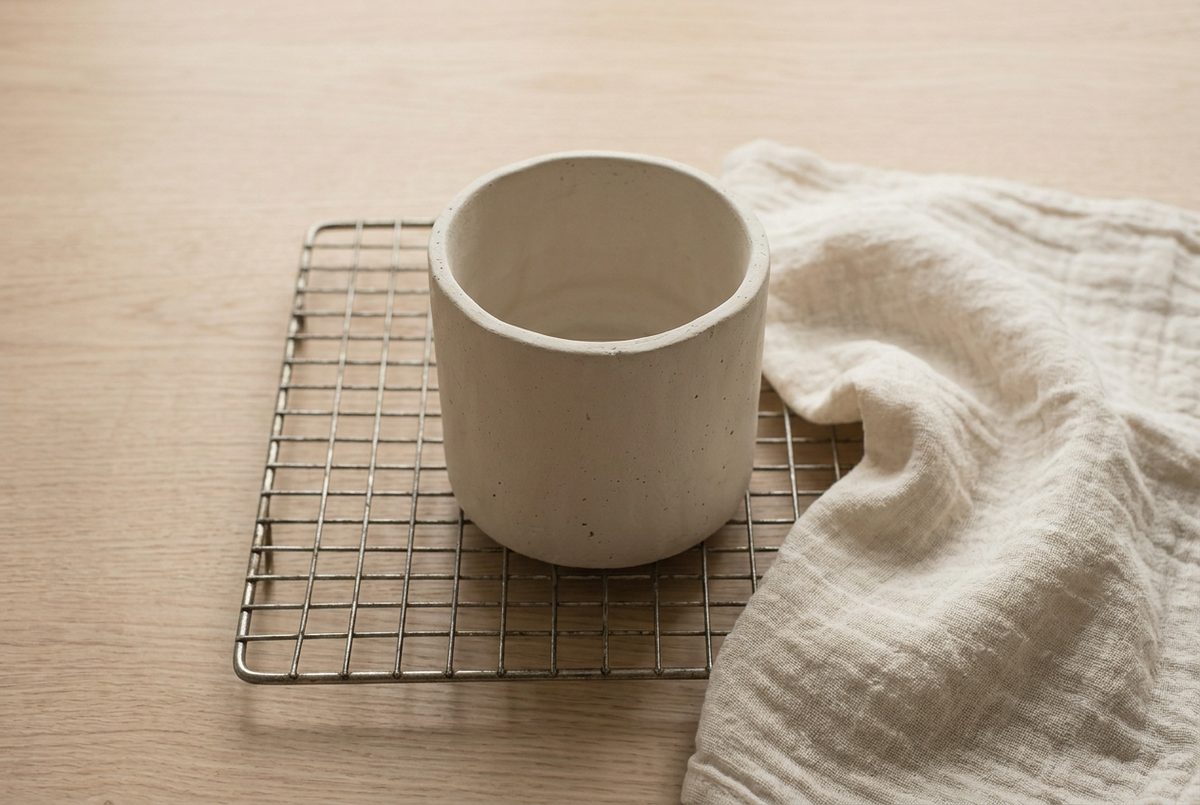 A clay plant pot drying on a wire rack away from direct heat