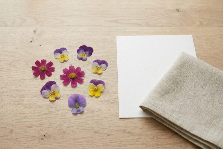 Pressed violas arranged on a pale oak desk beside blotting paper