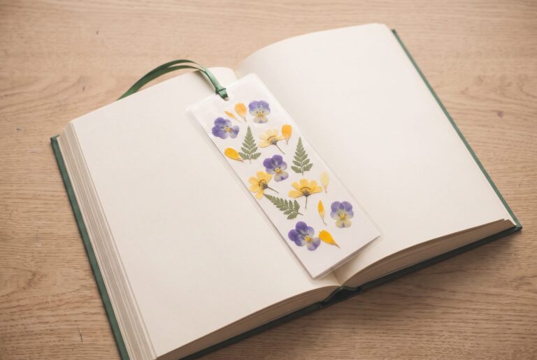 A finished pressed flower bookmark resting on the pages of an open book