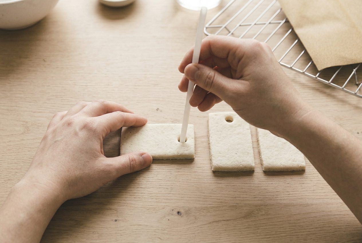 A straw punching a clean hole near the end of a cut dough shape